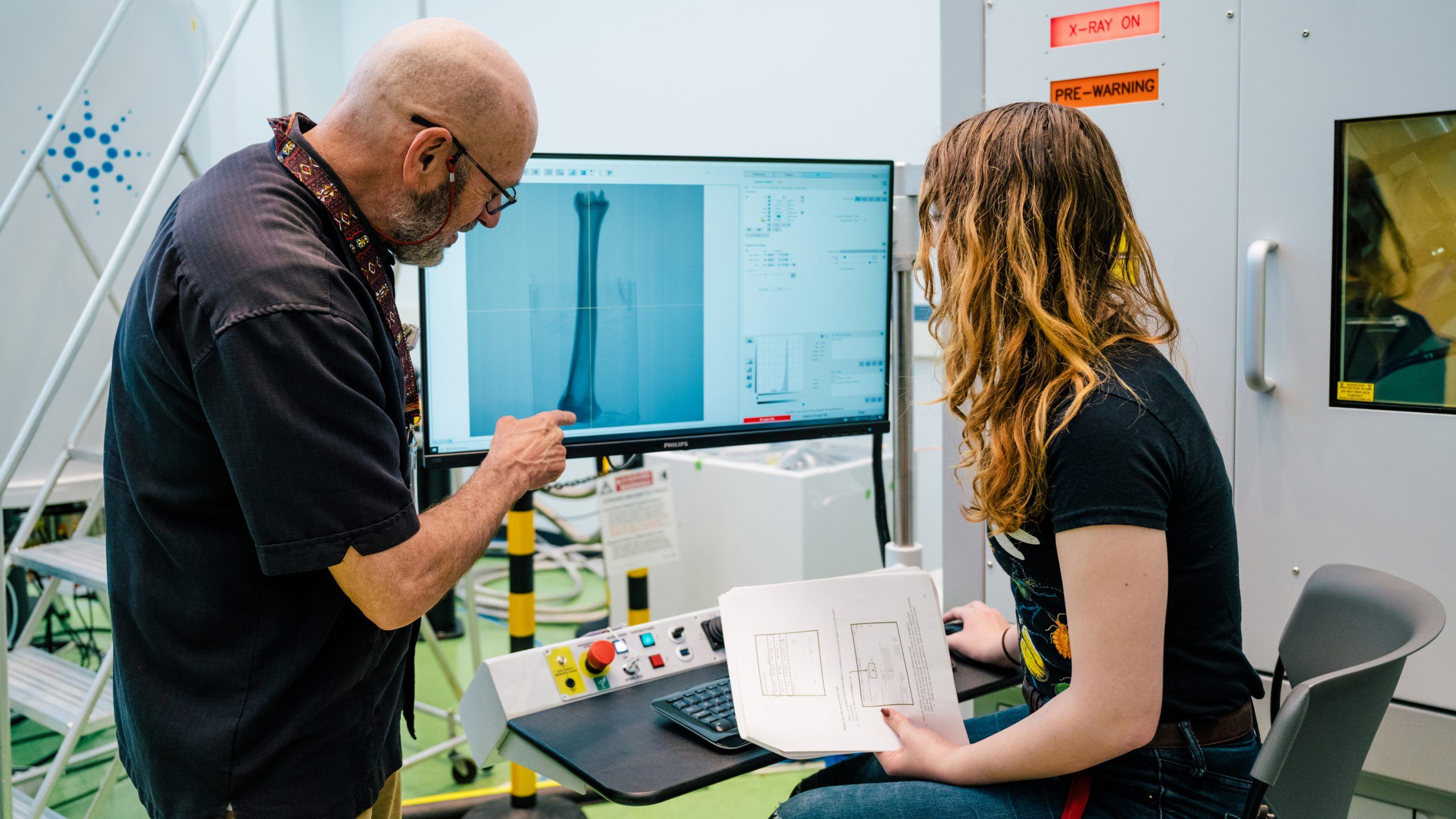 Two people in a lab examine a scan of a bone